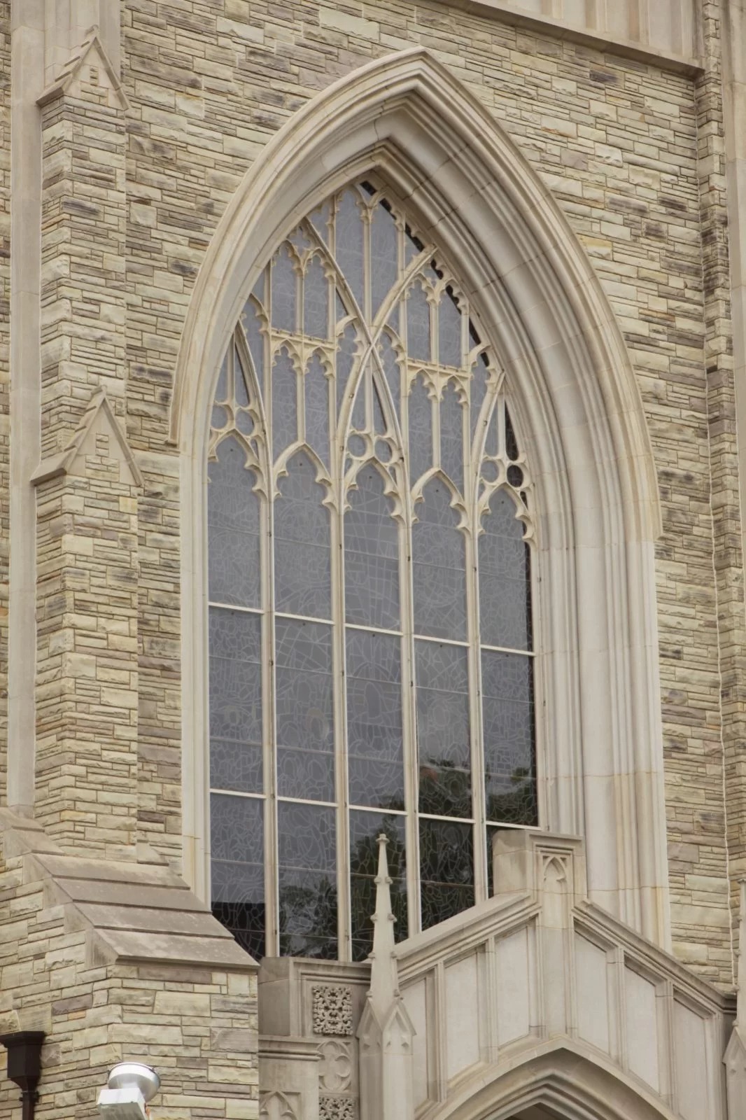 Gothic stained glass window with protective coverings in a church setting